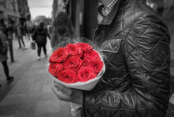 man holding red flowers