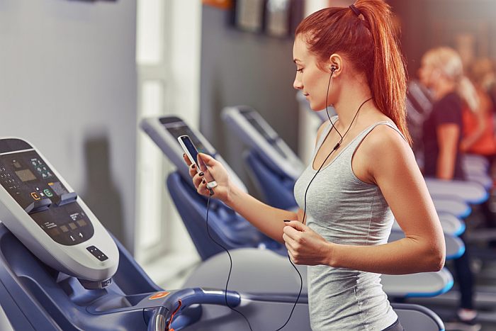 Girl running gym with smartphone