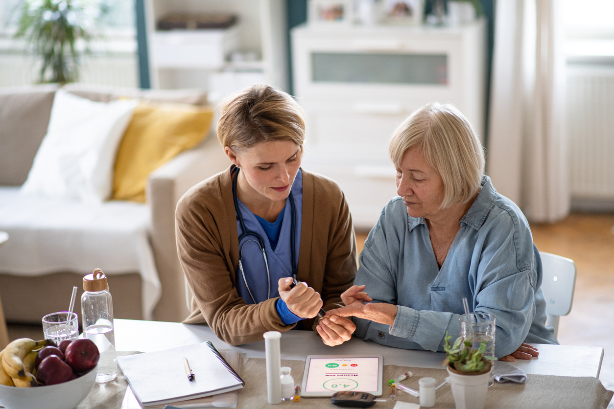 Nurse, caregiver or healthcare worker with senior woman patient, measuring blood glucose indoors.